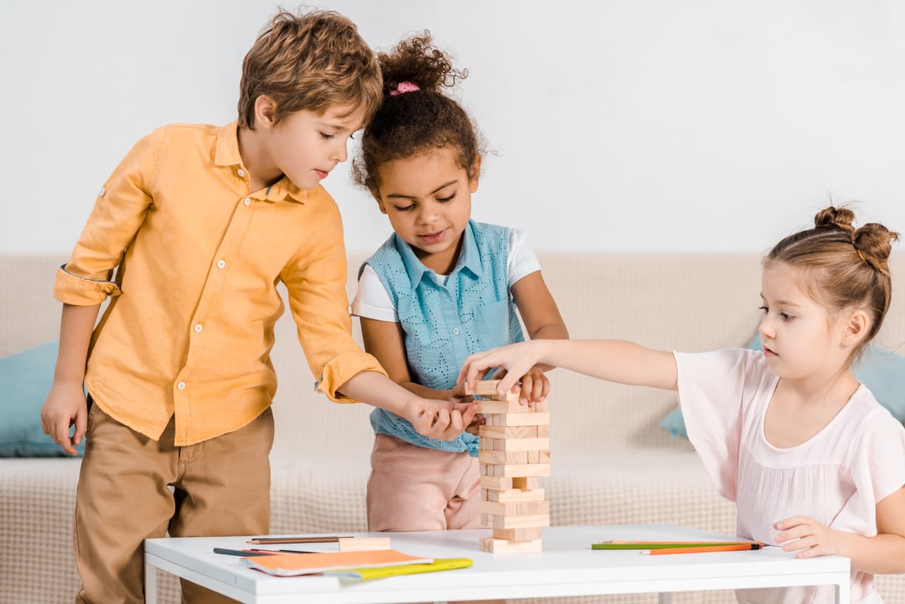 Drie diverse kinderen spelen samen met houten blokken